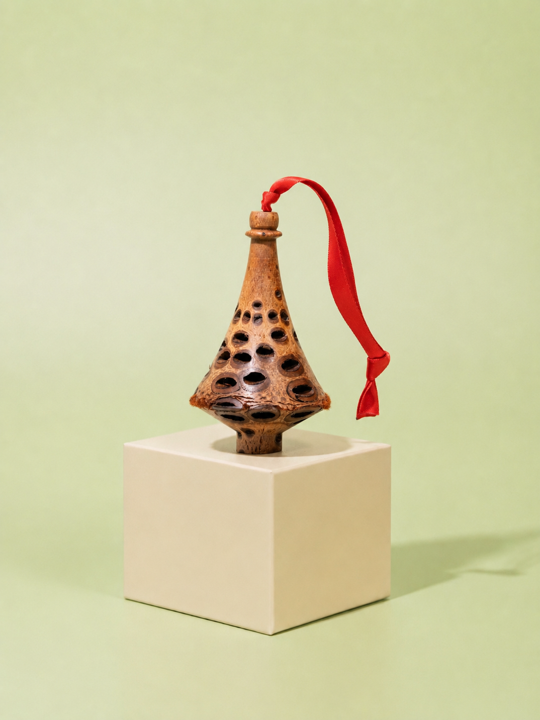 Handcrafted Banksia seed pod finial Christmas decoration with red ribbon on sage green
