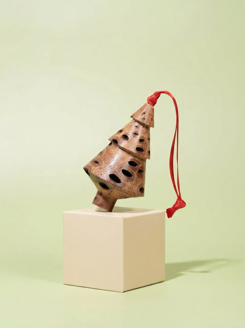 Tiered Banksia pod Christmas tree ornament with red ribbon on a green display pedestal